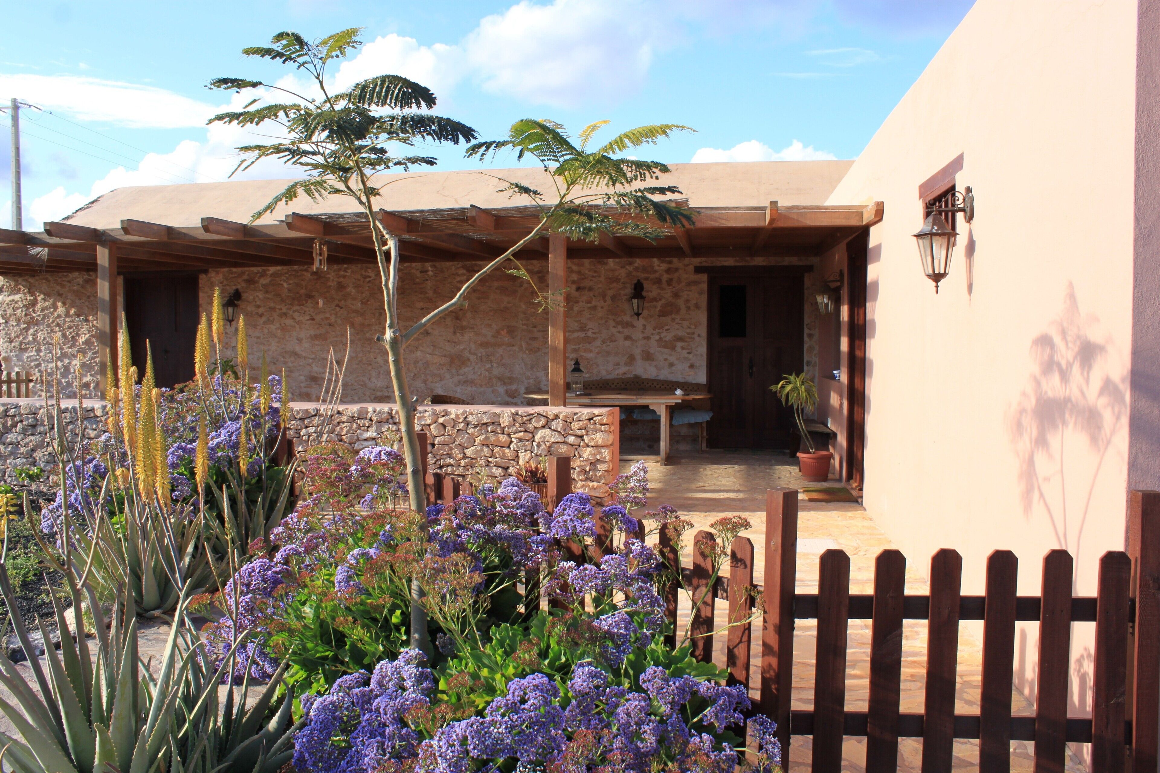 A building with a stone facade, wooden beams, and a patio area with potted plants and flowers.