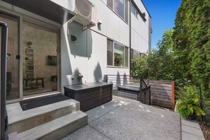 A modern building with a glass door entrance, a small outdoor seating area, and a staircase leading to the entrance. - Bright & Cozy Seward Park 1BR w/Rooftop Patio + AC (Seattle)