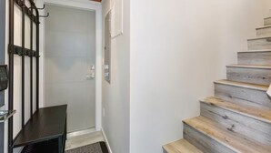 A staircase with wooden steps and a metal handrail, leading to a door with a glass panel. - Bright & Cozy Seward Park 1BR w/Rooftop Patio + AC (Seattle)