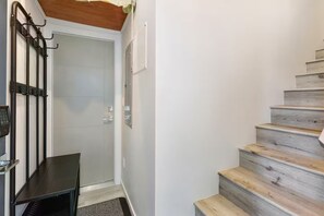 Eine Treppe mit Holzstufen und einem Metallgeländer, die zu einer Tür mit Glasscheibe führt.