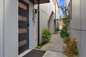 A narrow alleyway with a door labeled '5205C' and a small garden area with plants. - Bright & Cozy Seward Park 1BR w/Rooftop Patio + AC (Seattle)