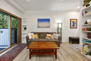 A modern living room with a grey sofa, wooden coffee table, and a bookshelf.