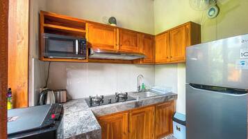 A kitchen with wooden cabinets, a microwave, a gas stove, a sink, and a refrigerator.