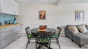 Eine moderne Küche mit Esstisch und Stühlen, einem grauen Sofa und zwei gerahmten Bildern an der Wand.