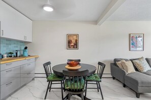 Eine moderne Küche mit Esstisch und Stühlen, einem grauen Sofa und zwei gerahmten Bildern an der Wand.