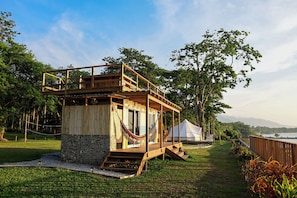 Una estructura de madera con balcón, pared de piedra y una hamaca.