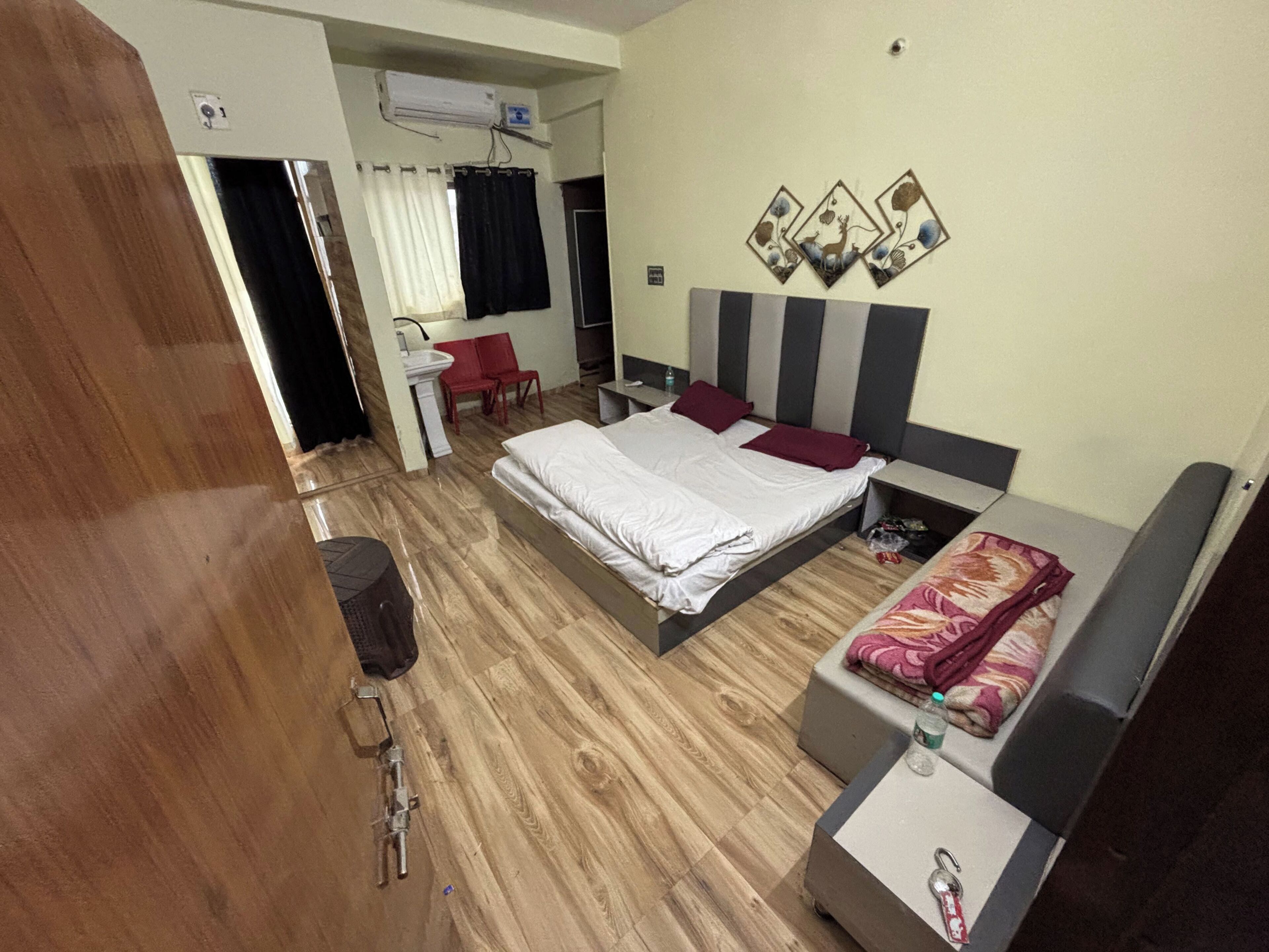Habitación de hotel con cama, sofá, escritorio y zona de ducha.