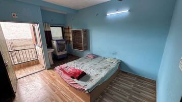 Un dormitorio con cama, ventilador de techo, ventana, armario y radiador.