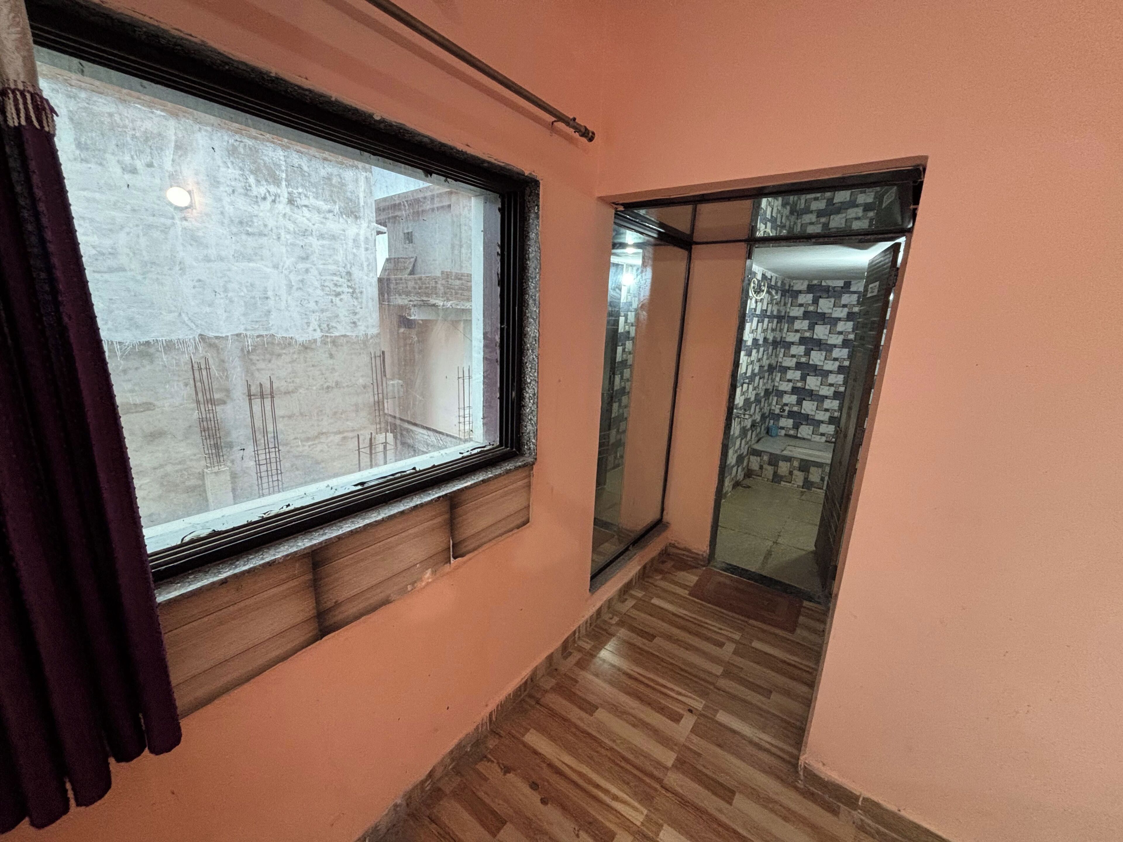 Un pasillo con ventanal, suelo de madera y pared de baldosas.