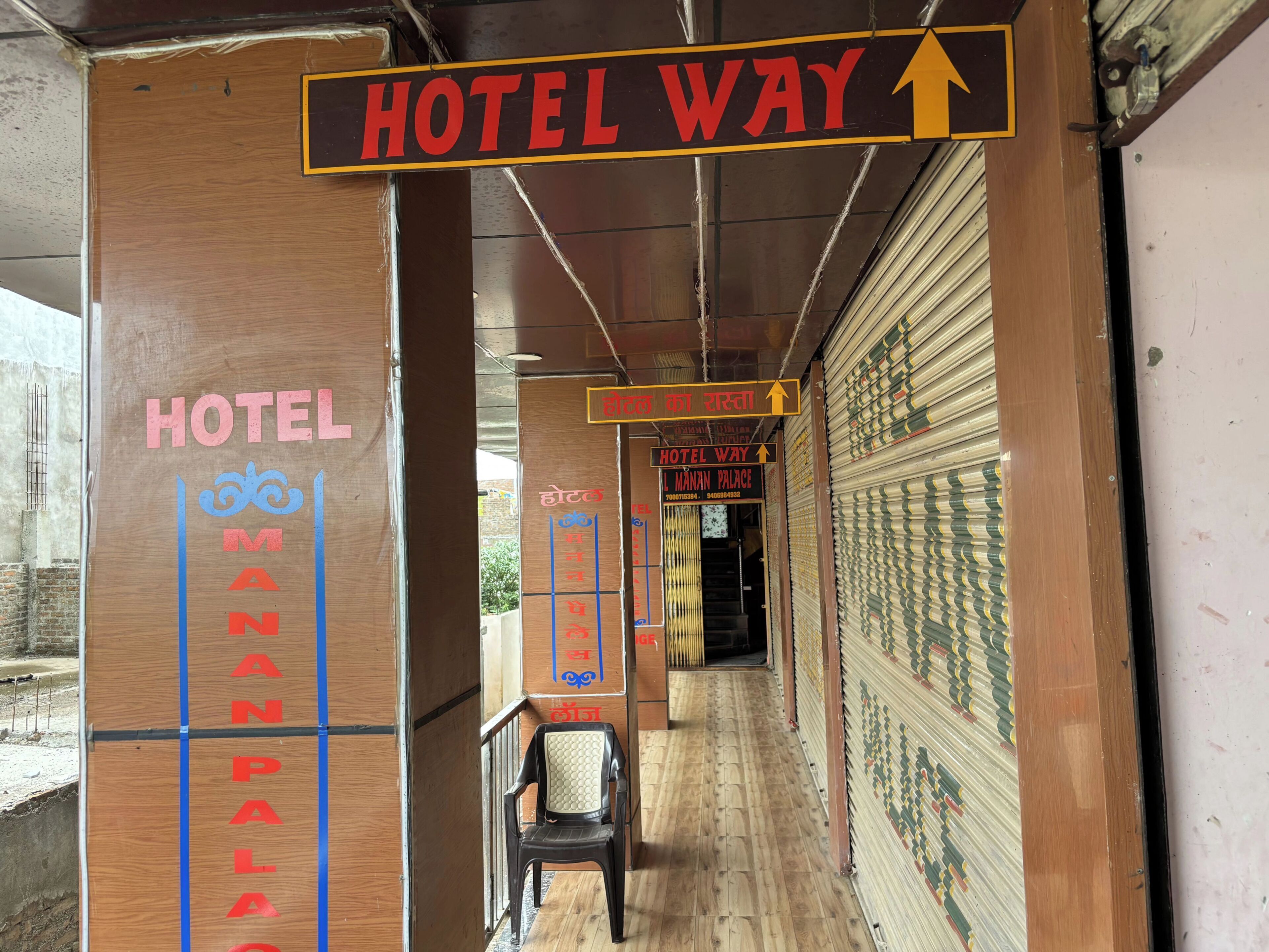 A hotel corridor with signs indicating directions to the hotel and a specific room, Manan Palace.