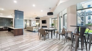 Cocina moderna con isla central, comedor con mesa y sillas redondas, y amplios ventanales con vistas al exterior.