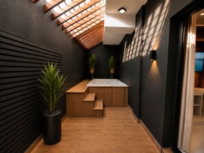 A modern bathroom with a wooden bench, a large bathtub, and two potted plants. - Modern 1BR Retreat with Private Jacuzzi & Patio up to, 4 guests allowed. (Santiago De Los Caballeros)