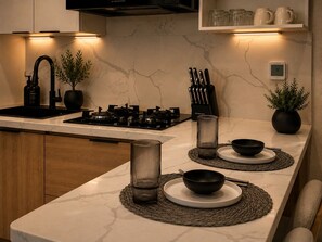 A modern kitchen with a marble countertop, a gas stove, a sink, and a built-in range hood. - Modern 1BR Retreat with Private Jacuzzi & Patio up to, 4 guests allowed. (Santiago De Los Caballeros)