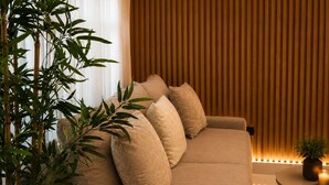 A modern living room with a sofa, cushions, a round coffee table, and a potted plant. - Modern 1BR Retreat with Private Jacuzzi & Patio up to, 4 guests allowed. (Santiago De Los Caballeros)