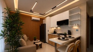 A modern kitchen with a built-in stove, a microwave, and a black refrigerator. There is a wooden dining area with two chairs and a small table. - Modern 1BR Retreat with Private Jacuzzi & Patio up to, 4 guests allowed. (Santiago De Los Caballeros)