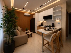 A modern kitchen with a built-in stove, a microwave, and a black refrigerator. There is a wooden dining area with two chairs and a small table. - Modern 1BR Retreat with Private Jacuzzi & Patio up to, 4 guests allowed. (Santiago De Los Caballeros)