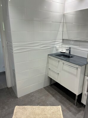 Ein modernes Badezimmer mit weißen Fliesen, einem schwarzen Waschtisch und einem beigen Teppichboden.