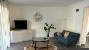 A modern living room with a TV, sofa, and a round table with stools. - TO THE SOUND OF BIRDSONG House in Provence with private garden and parking (Les Pennes-Mirabeau)
