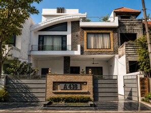 A modern two-story house with a balcony, a stone facade, and a gated entrance. - The Golden Window Villa (Amritsar)