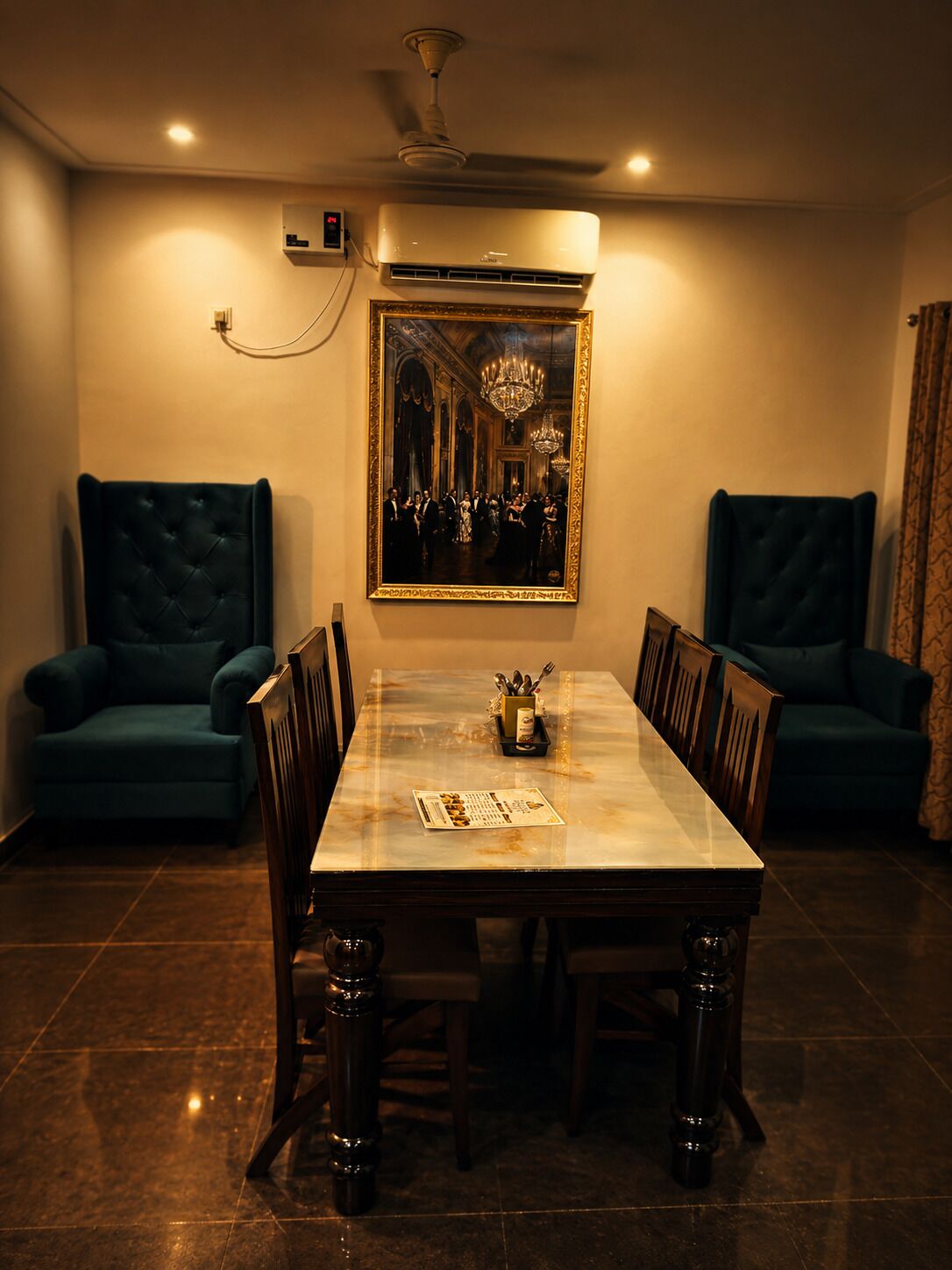 A dining room with a marble table, upholstered chairs, a chandelier, and a painting on the wall.