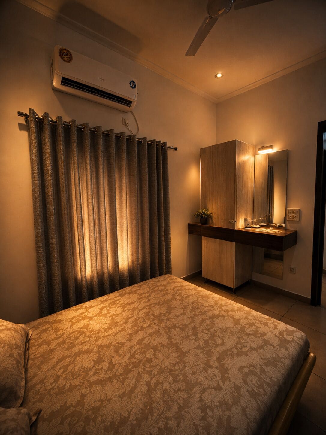 A bedroom with a bed, a vanity with a mirror, and an air conditioning unit on the wall.
