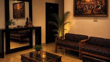 A room with a sofa, a table with a candle, a mirror, and a painting on the wall.