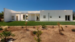 Un edificio moderno con tetto piatto, pareti esterne bianche e un prato curato.