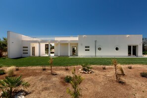 A modern building with a flat roof, white exterior walls, and a well-maintained lawn. - Trullo Elisa by Perle di Puglia (Carovigno)