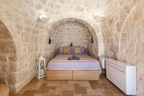 A stone-walled room with a bed, a white radiator, and a lantern. - Trullo Elisa by Perle di Puglia (Carovigno)