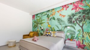 Una camera da letto con un letto, un comodino, uno sgabello e una parete decorata con un murale tropicale.