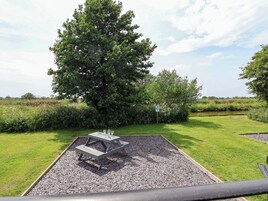A picnic table with a gravel base surrounded by grass and trees.