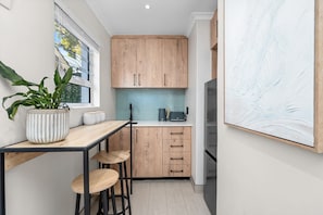 A modern kitchen with wooden cabinets, a countertop, a potted plant, and a refrigerator. - Sangrove Residence - Four Bedroom House, Sleeps 8 (Cape Town)