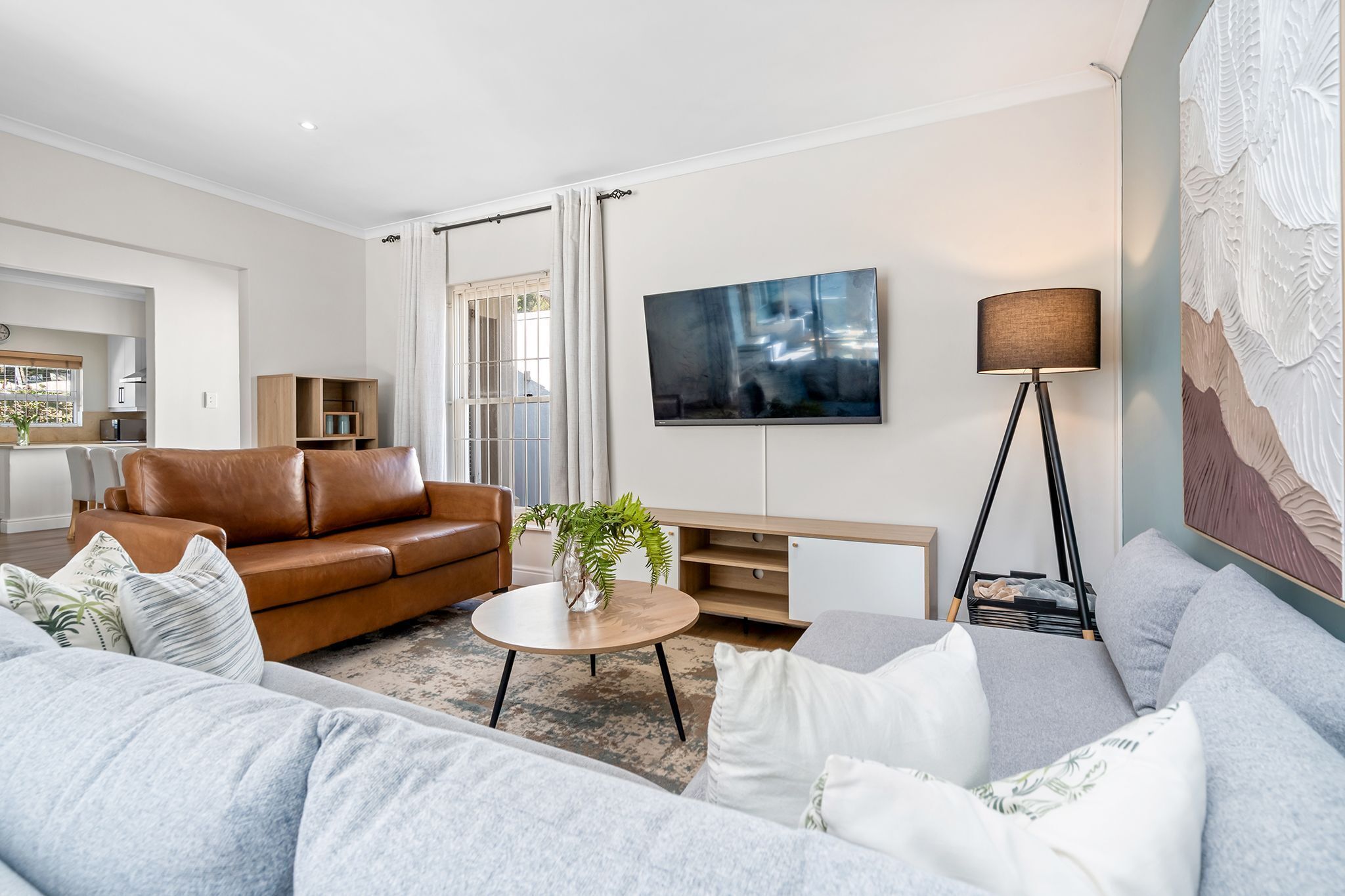 Ein modernes Wohnzimmer mit einem Ledersofa, einem runden Couchtisch und einem grauen Sofa.
