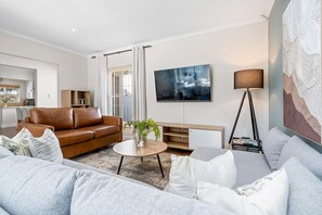 Ein modernes Wohnzimmer mit einem Ledersofa, einem runden Couchtisch und einem grauen Sofa.
