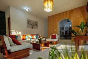 A modern living room with a sofa set, a coffee table, and a dining area with a wooden table and chairs. - Spacious House | 7 BR | Pool, Gym & Terrace (Mérida)