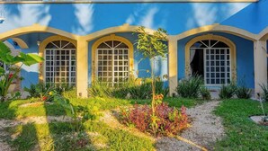Un bâtiment doté de trois fenêtres en arc de cercle et d’un jardin à l’avant.