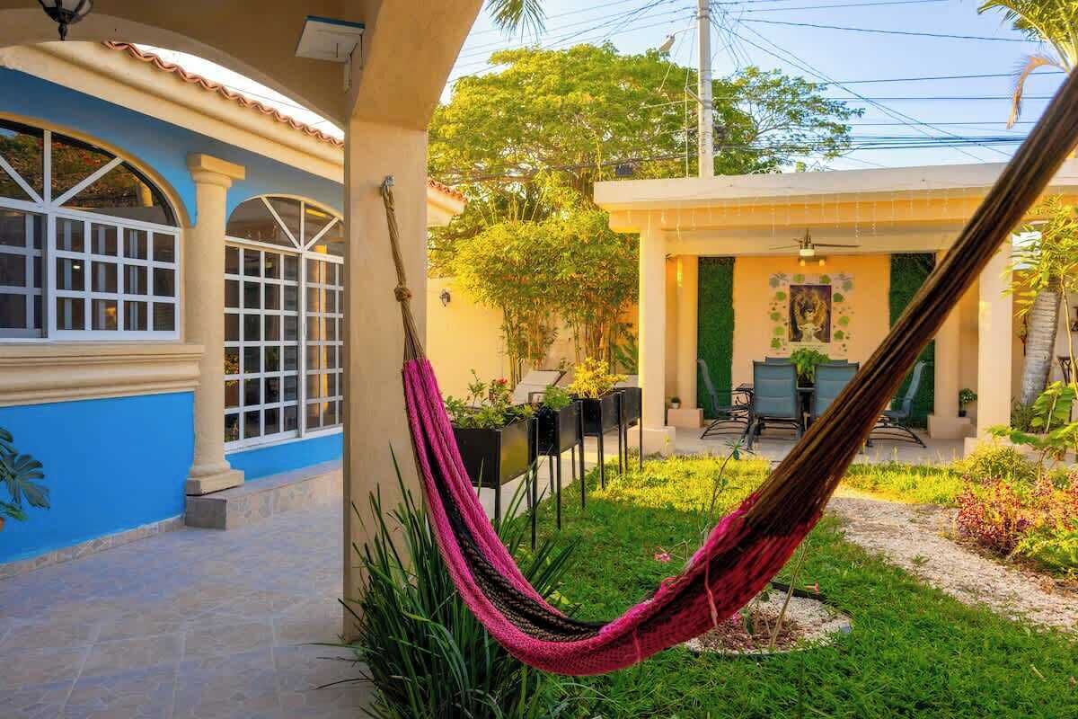 A courtyard with a hammock, outdoor seating, and a building with a blue facade.