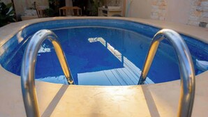 A swimming pool with metal ladders, surrounded by a stone wall and indoor plants. - Spacious House | 4 BR | Pool, Gym & Terrace (Mérida)