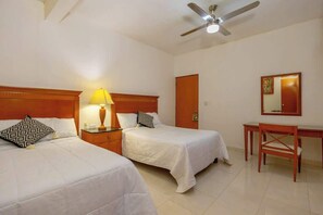 A hotel room with two beds, a desk, a chair, a ceiling fan, and a lamp. - Spacious House | 4 BR | Pool, Gym & Terrace (Mérida)
