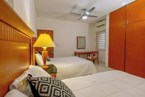 Ein Hotelzimmer mit zwei Betten, einem Schreibtisch, einem Stuhl, einer Lampe und einem Kleiderschrank.