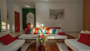 A modern living room with a sofa set, a coffee table, and a wall with a floral painting. - Spacious House | 4 BR | Pool, Gym & Terrace (Mérida)