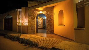 Un bâtiment doté d’une façade en pierre, d’une entrée en arc de cercle et d’un chemin menant à une porte.