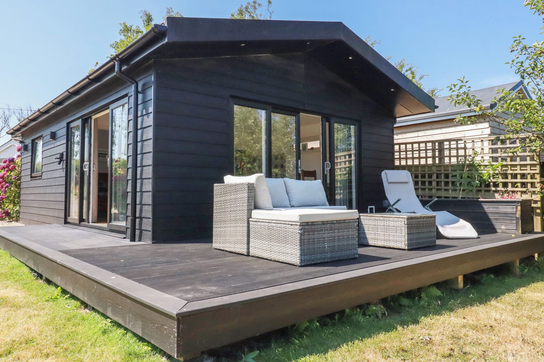 A modern house with a deck, large windows, and outdoor furniture.