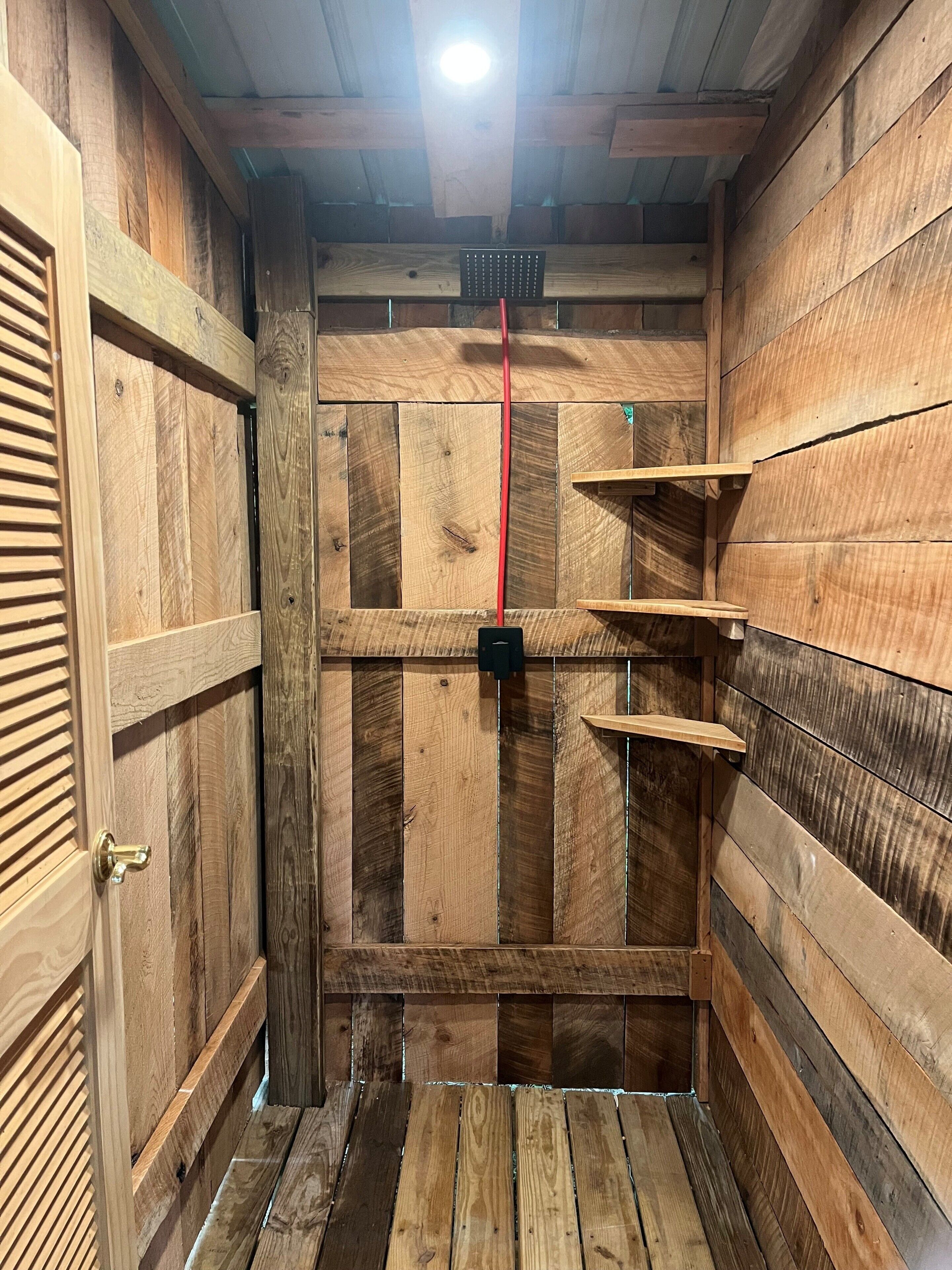 Une pièce en bois avec une porte, un cordon rouge et un objet noir accroché au mur.