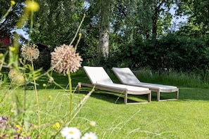 Two lounge chairs on a grassy lawn with trees in the background. - Four Cows Vacation Home – A Rural Retreat Near the Baltic Sea (Esgrus)