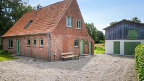 Une maison en briques avec un toit en pente, une allée en gravier et un banc en bois.