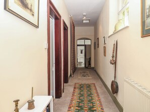 A hallway with a patterned carpet, wooden doors, and a radiator. - Lukesland Wing (Ivybridge)