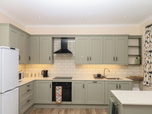 A kitchen with light-colored cabinets, a black range hood, a dishwasher, and a microwave. - Lukesland Wing (Ivybridge)
