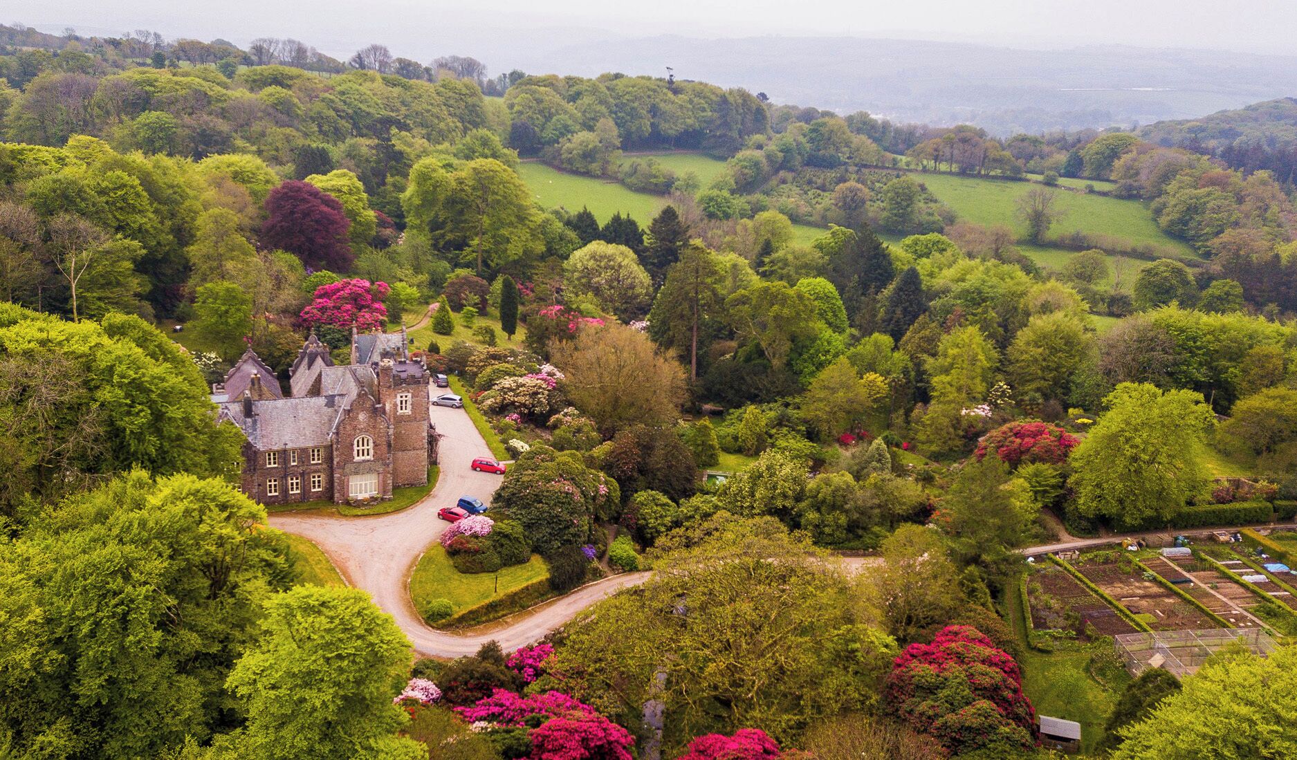 A large estate with a prominent building surrounded by lush greenery and a well-maintained garden.