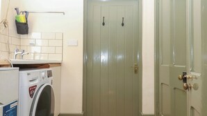 A laundry area with a washing machine, a sink, and a door. - Lukesland Wing (Ivybridge)